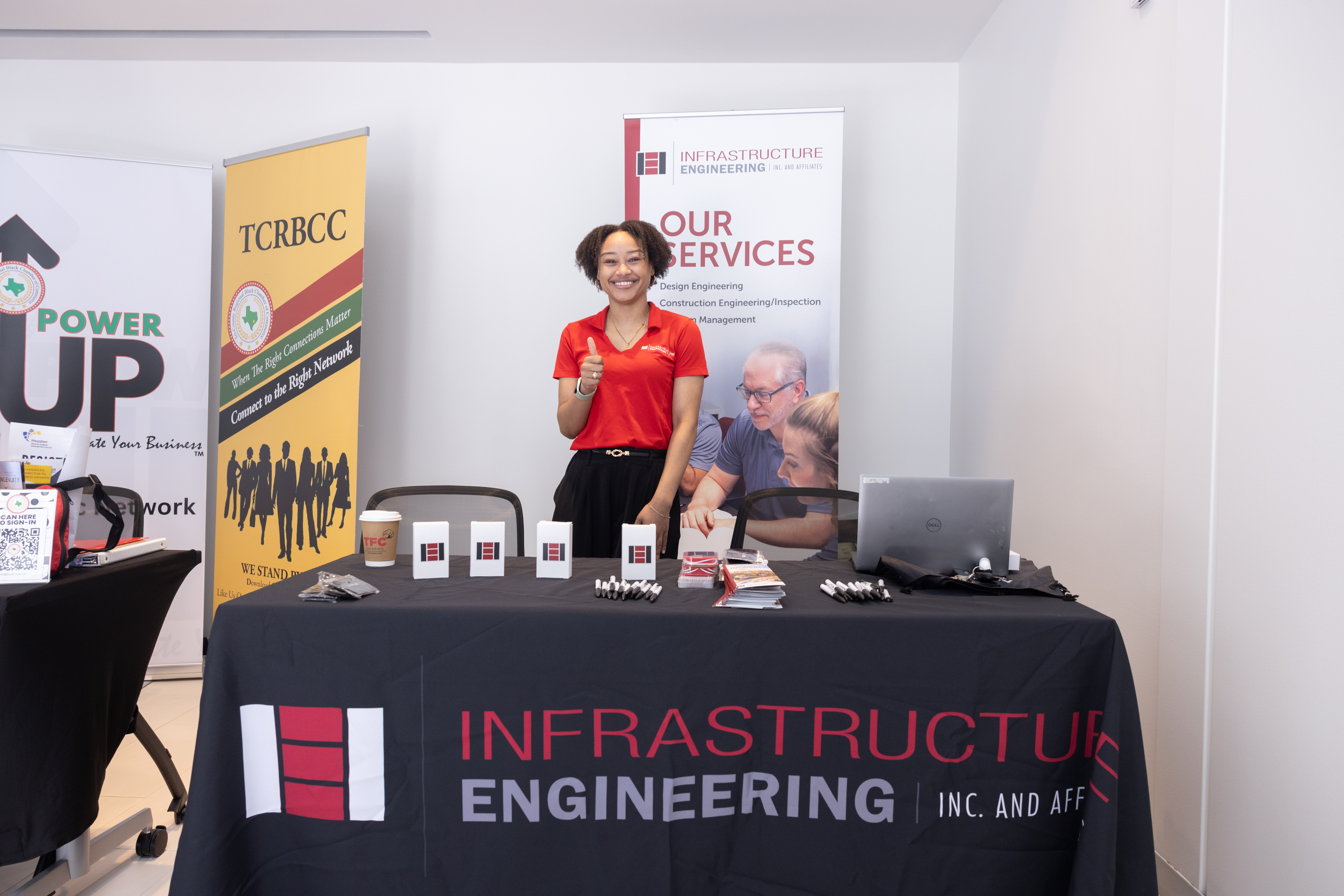 Exhibitor smiling and giving a thumbs up at the Infrastructure Engineering Inc. booth